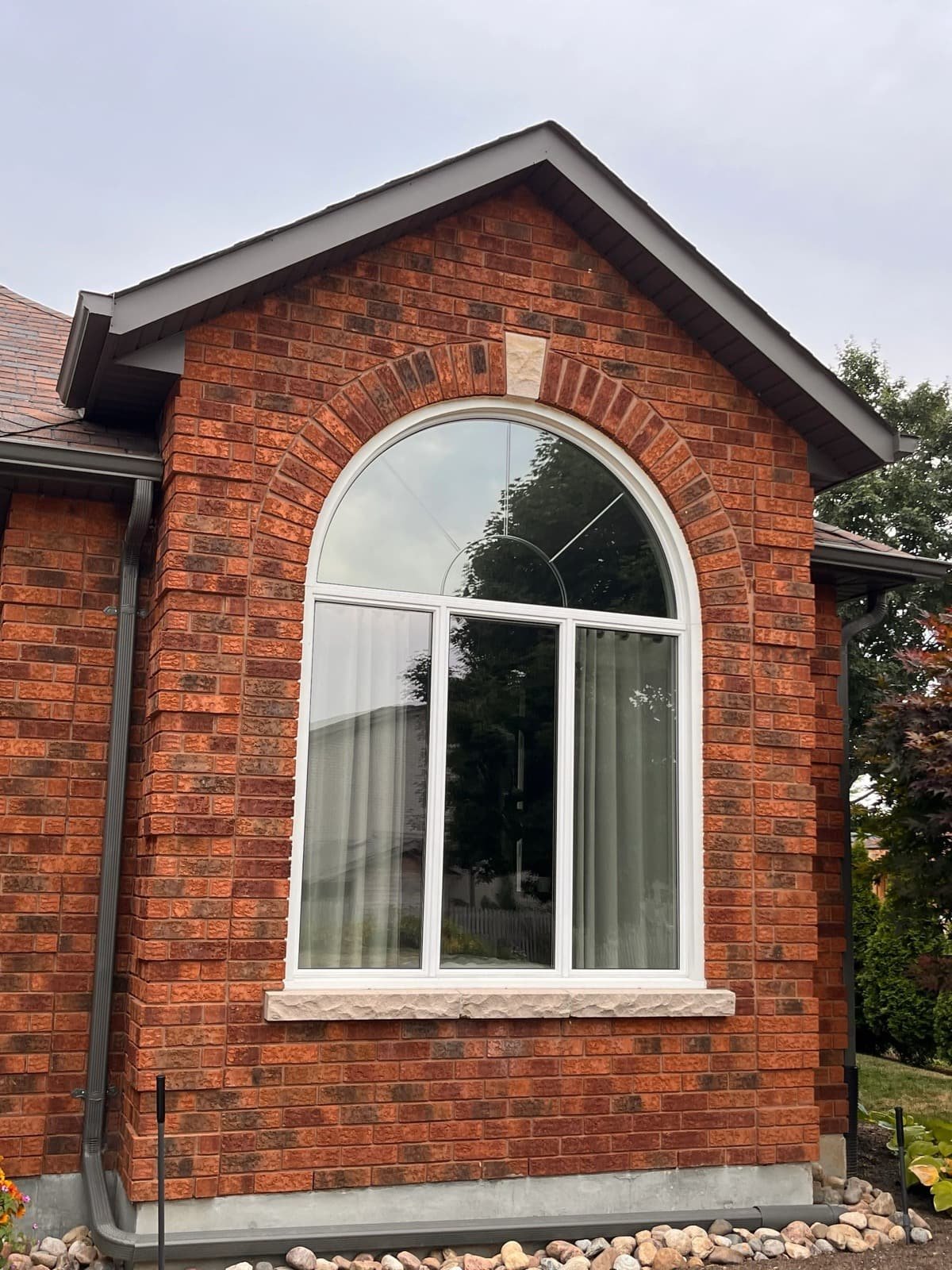 Arched window on a red brick home with window film