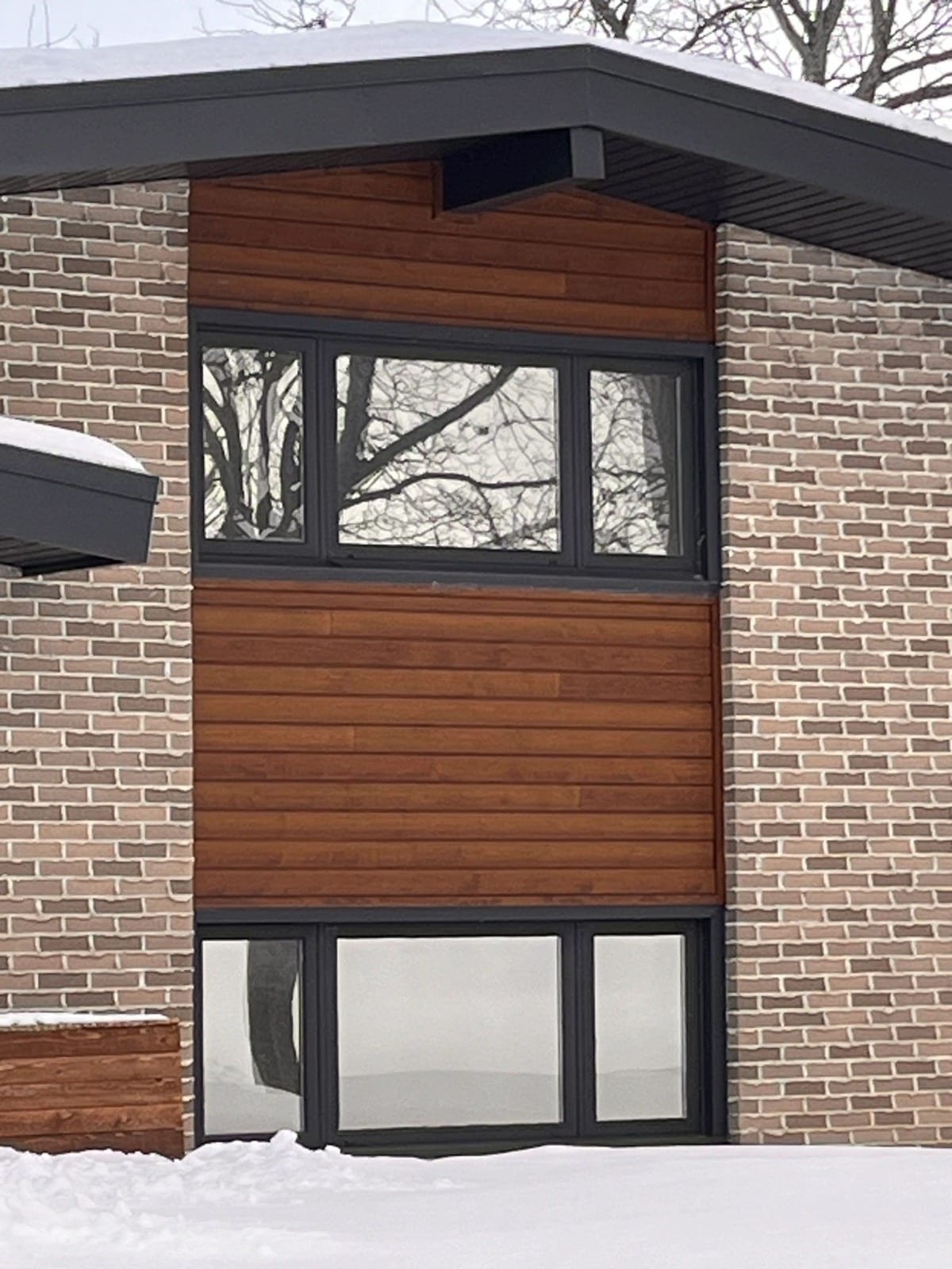 Modern brick home with dark tinted windows in winter